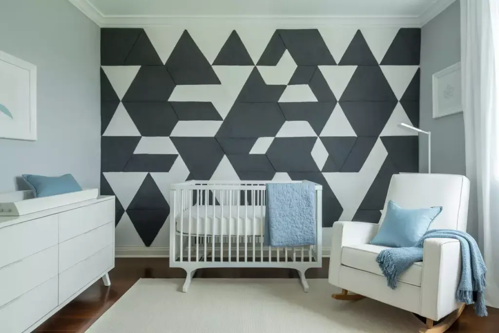 Modern nursery with geometric black and white wall, white crib, dresser, armchair, and blue accents.