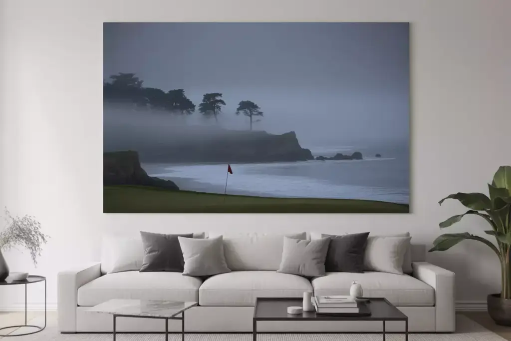 Large wall art of a misty coastal golf course hangs above a modern white sofa with gray cushions.