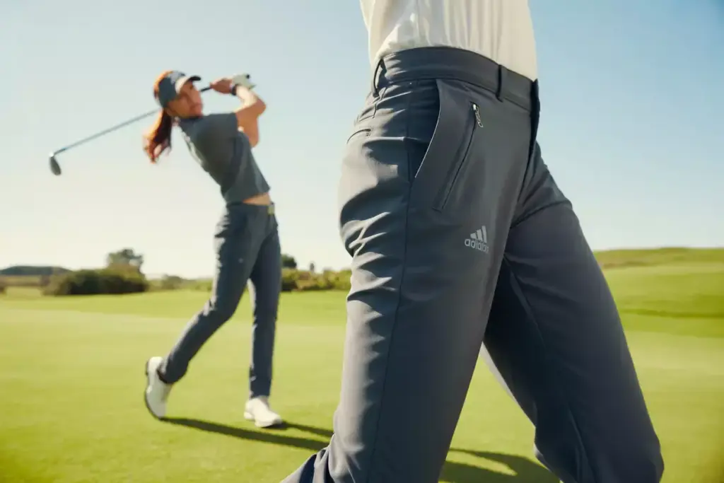 Serious female golfer mid swing wearing ultimate365 tour pants on sunny fairway