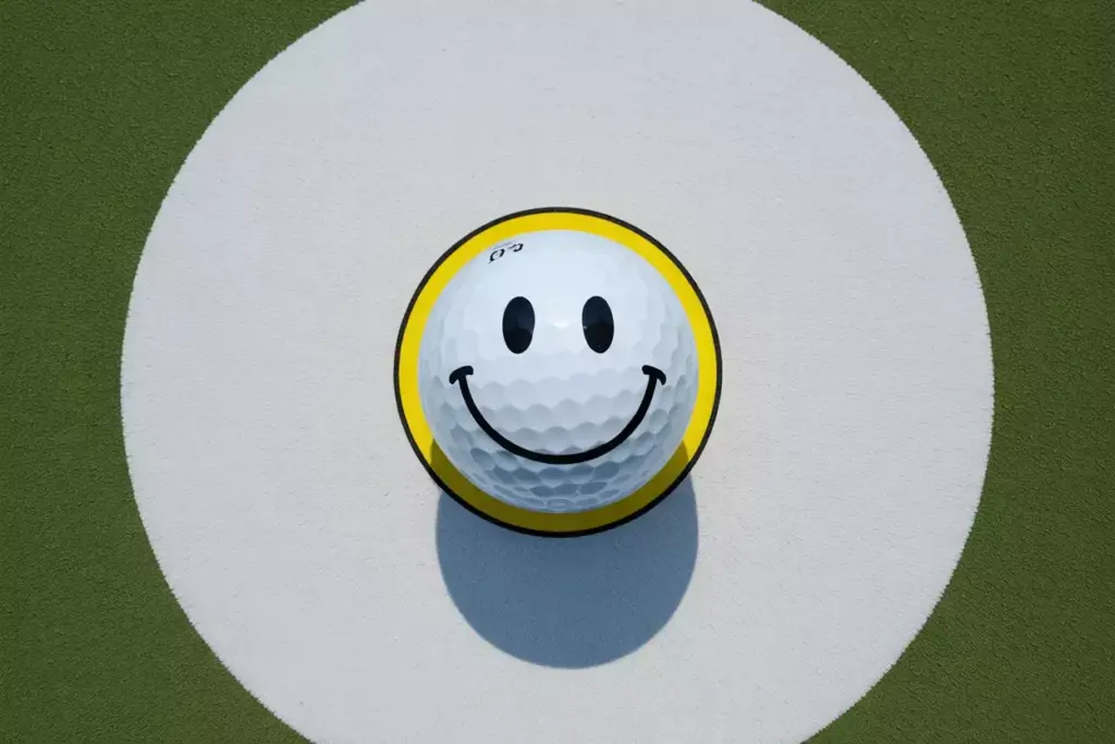 Classic yellow smiley face on white golf ball