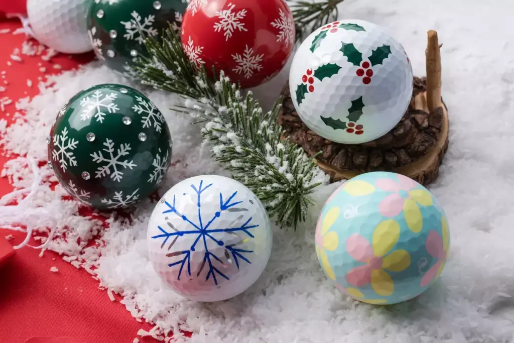 Holiday themed golf balls on snow with pine needles
