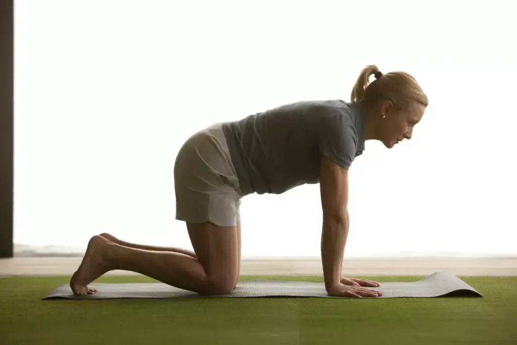 A Golfer Performing Cat Cow Yoga Pose On A Mat For Spinal Mobility And Posture Warm Up
