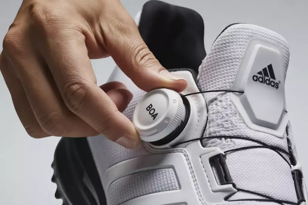 Close up of hand adjusting boa fit system dial on adidas codechaos shoe