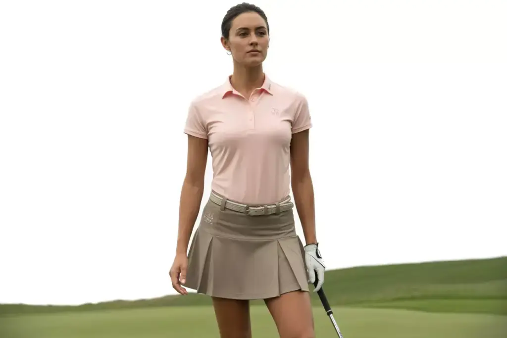 Woman on tee box wearing pink polo and khaki pleated skort