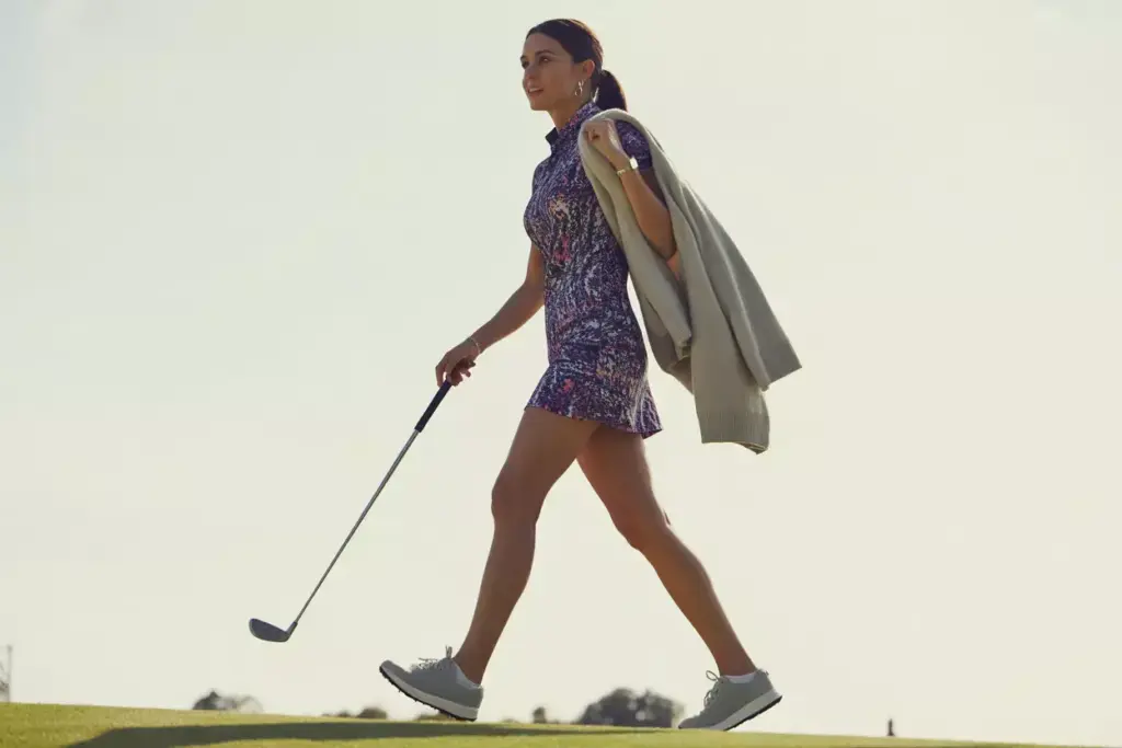 Woman in patterned golf dress walking from course to clubhouse