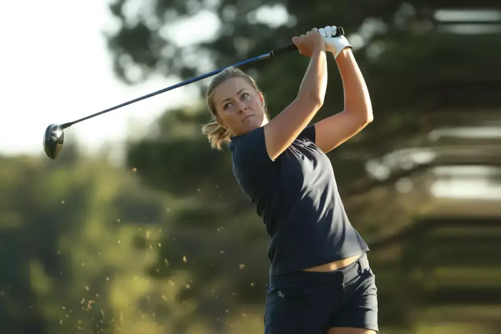Female Golfer At Top Of Backswing Showing Controlled Tempo And Balance