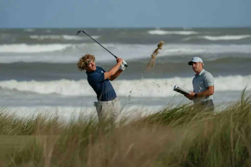 Golfer Swinging In Strong Winds On Coastal Ocean Course Hole