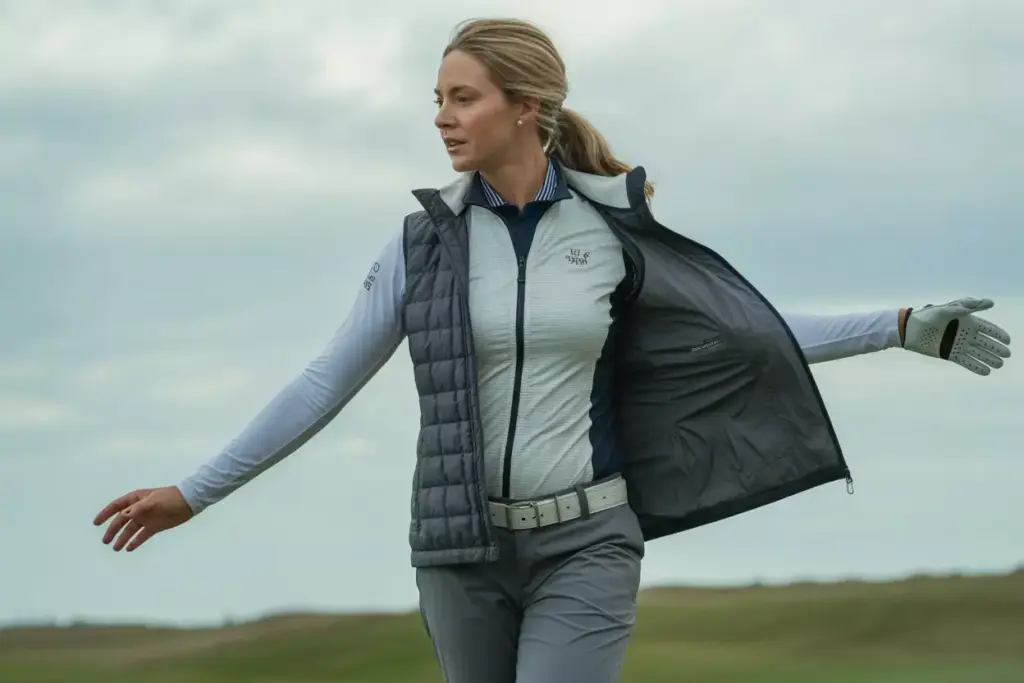 Golfer in layers adjusting jacket on windy course