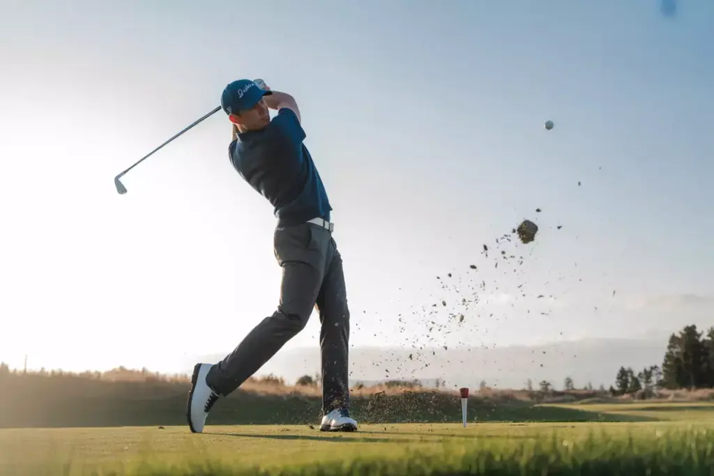 The Dynamic Mid Swing Capture Of A Golfer At The Peak Of Their Swing With Club In Motion On A Golf Course During Golden Hour