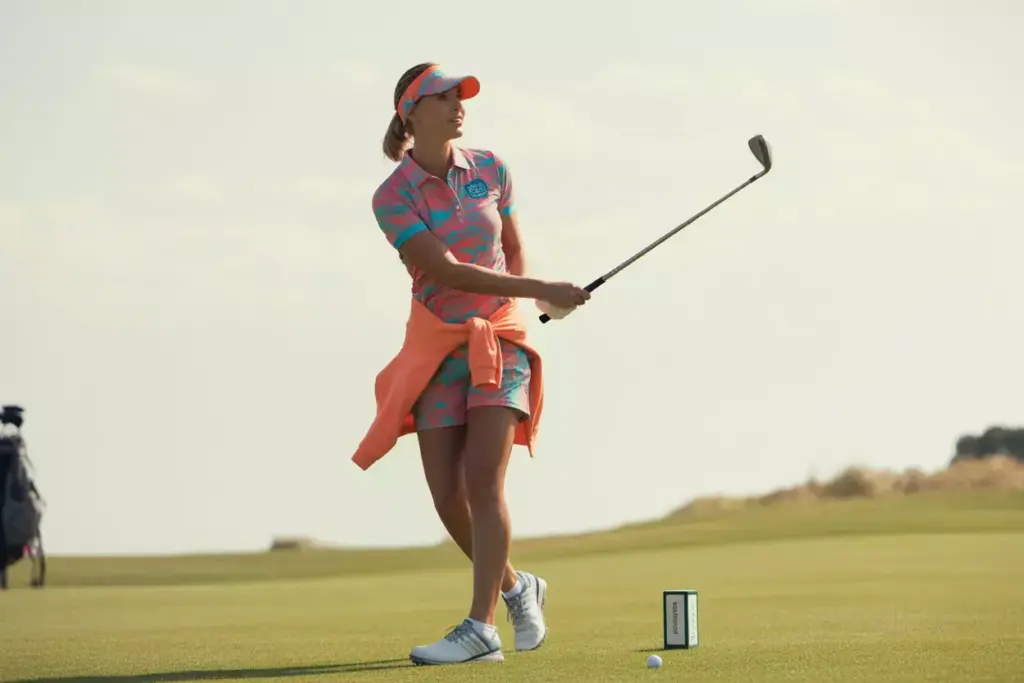 Woman in bright polo swings on sunny public golf course