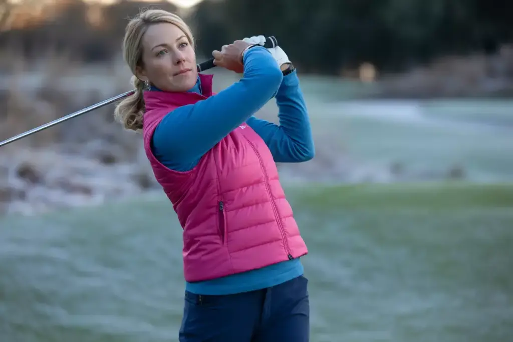 Female golfer swinging in quarter zip fleece mid layer on frosty fairway