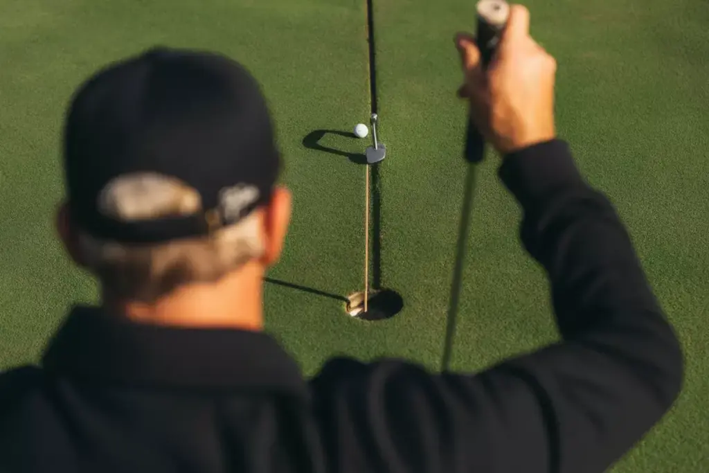 A Golfer In Putting Stance Focused On The Ball Shot From Behind And To The Side