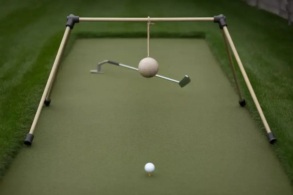 A Golf Ball Approaching A Swinging Pendulum Obstacle On A Diy Backyard Putting Green