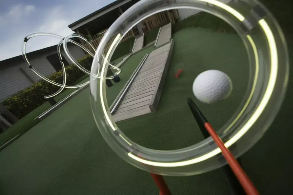 A Golf Ball Zooming Through A Lit Pvc Loop The Loop Obstacle On A Turf Course