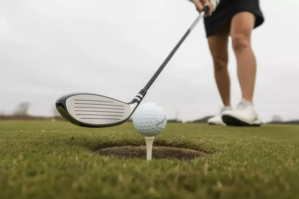 A Womens Fairway Wood Making Contact With A Golf Ball On A Lush Green Fairway