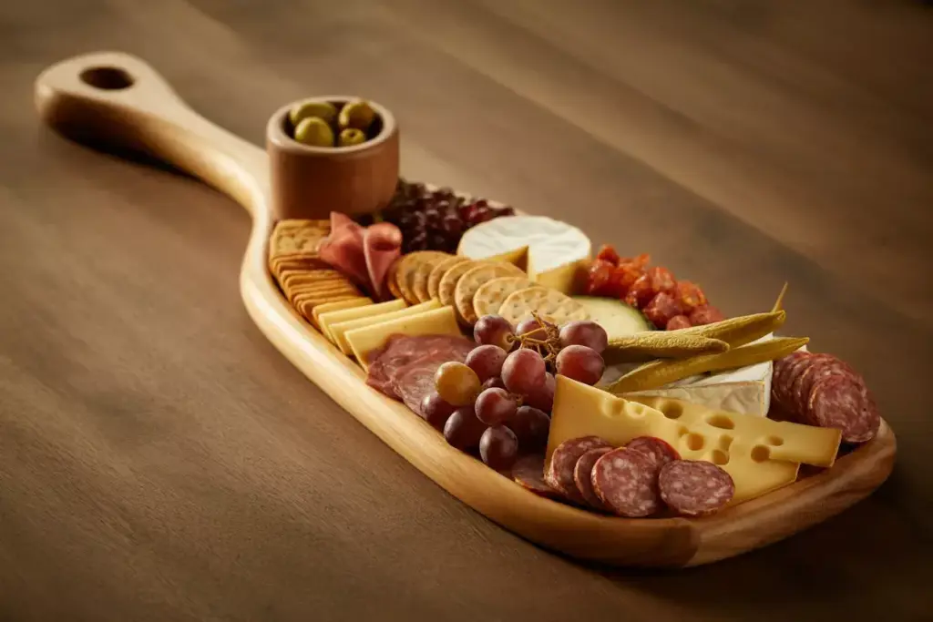 An Elongated Golf Club Shaped Wooden Charcuterie Board With Meats Cheeses And Grapes